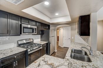 A kitchen with black cabinets and granite countertops. at San Montego Apartments, Mesa, AZ